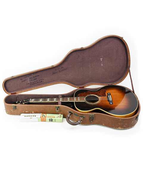 1952 Gibson J-185 guitar and case on a white surface, emphasizing the instrument's timeless vintage style.
