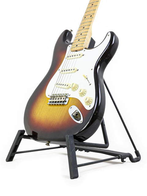 1958 Fender Stratocaster guitar resting on a stand, featuring a striking white background that enhances its vintage appeal.

