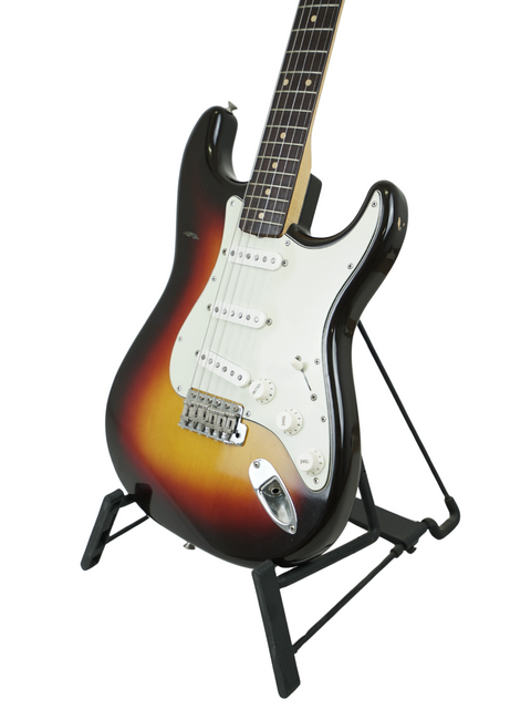 1961 Fender Stratocaster guitar resting on a stand, beautifully contrasted by a deep black background.