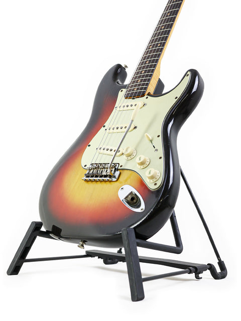1963 Fender L-Series Stratocaster guitar resting on a stand, set against a simple white background.