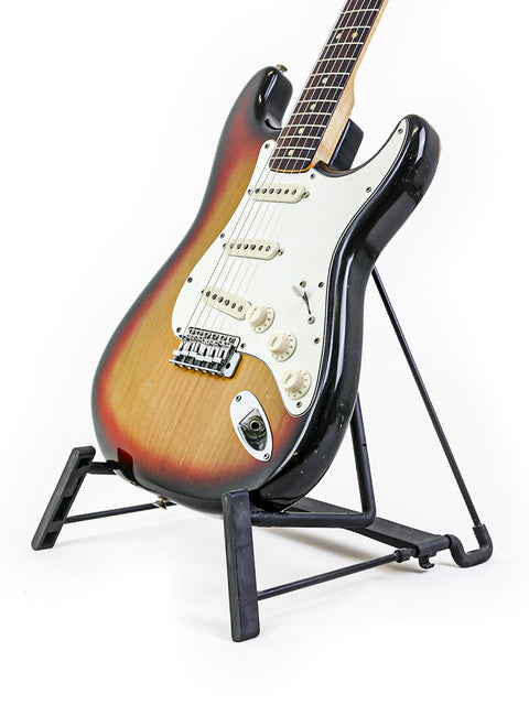 1974 Fender Stratocaster guitar elegantly positioned on a stand with a white background.