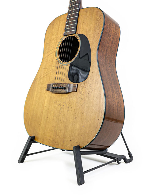 1974 Martin D-18 guitar resting on a stand, set against a simple white background.