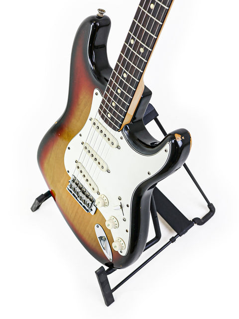 1974 vintage Fender Stratocaster guitar elegantly positioned on a stand with a white background.