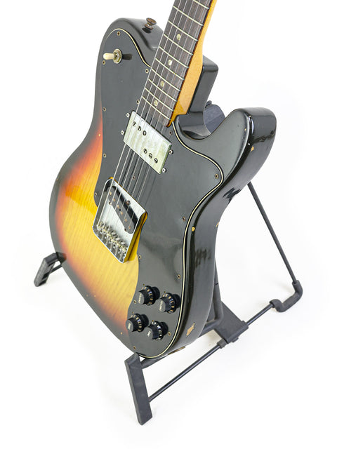 1977 Fender Telecaster Custom guitar with a sleek black body and a vibrant sunburst neck, exemplifying vintage craftsmanship.