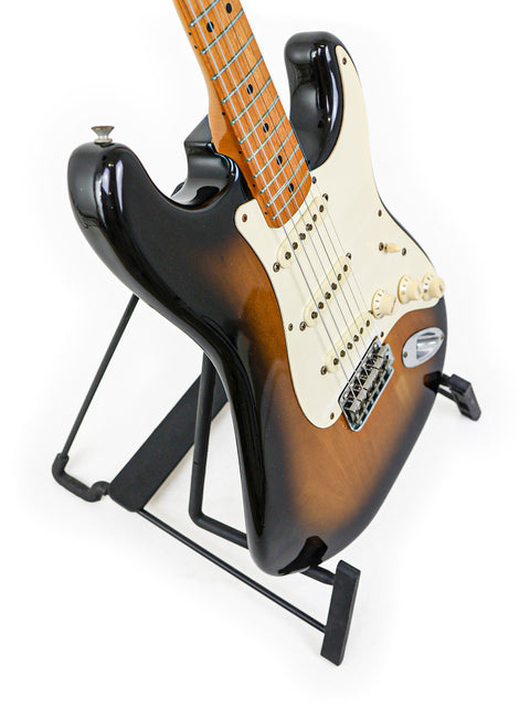 1982 Fender AVRI ‘57 Stratocaster resting on a stand, highlighted by a black background.