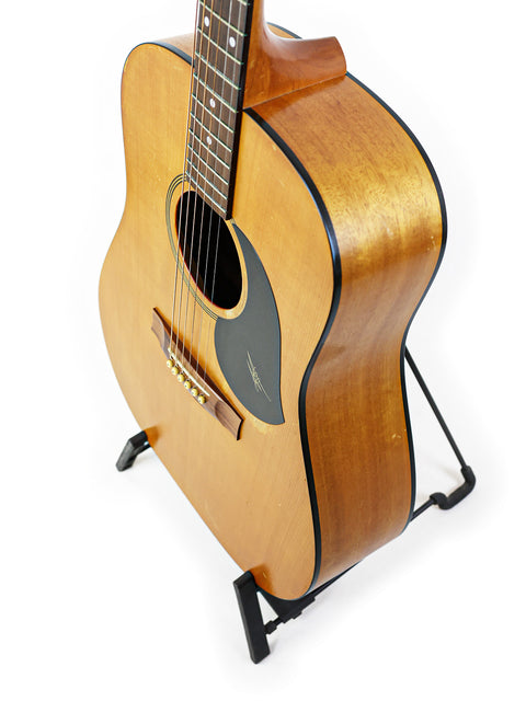 1996 Maton M225 guitar on a stand, highlighted by a stark white background for a clean look.