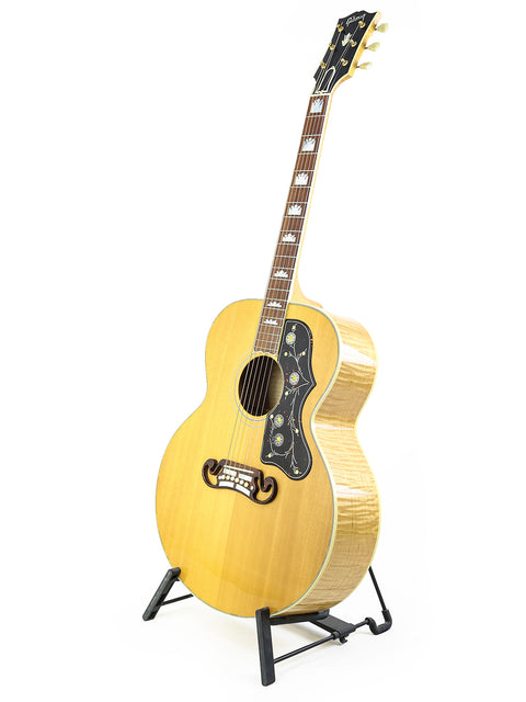 1999 Gibson SJ-200 guitar resting on a stand, set against a bright white backdrop