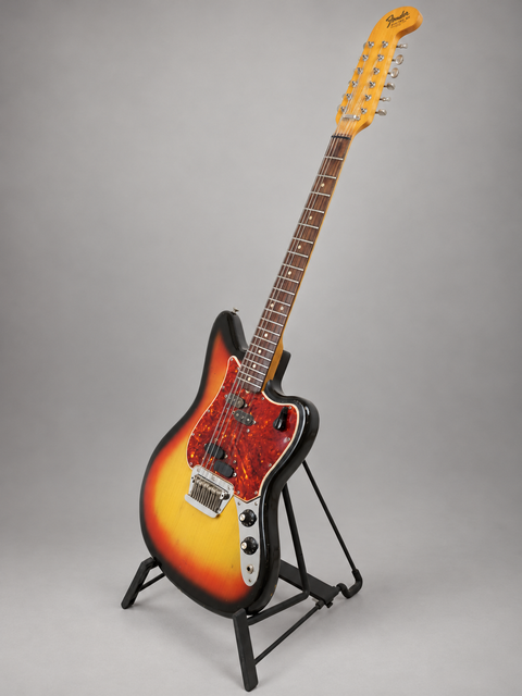 A stunning sunburst-finished 1965 Fender Electric XII guitar on a stand, highlighting its vintage appeal.