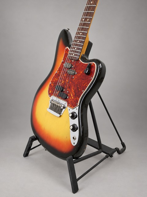 A stunning sunburst Fender Electric XII guitar from 1965, proudly positioned on a stand, ready to play.