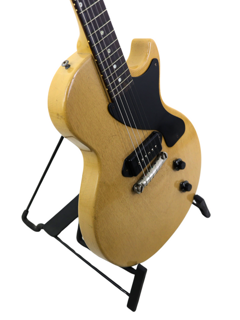 A 1956 Gibson Les Paul Jr electric guitar in TV Yellow, prominently positioned on a stand, highlighting its vintage appeal.