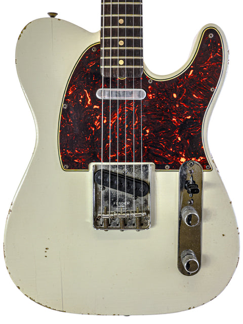 A 1963 USA Fender Telecaster guitar, showcasing a white finish with striking red and black paint designs.

