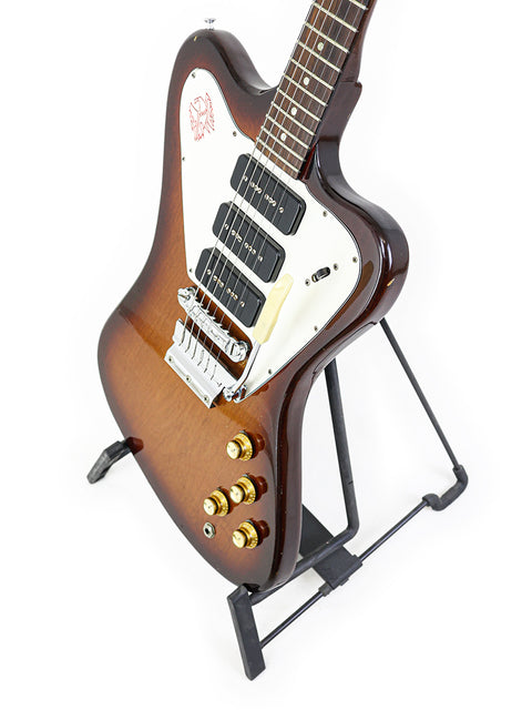 A 1966 Gibson Non Reverse Firebird III guitar displayed on a stand with a white backdrop.