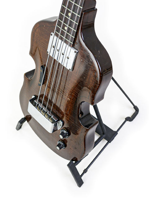 A 1969 Vintage Gibson EB-1 bass guitar elegantly displayed on a stand, set against a bright white backdrop.
