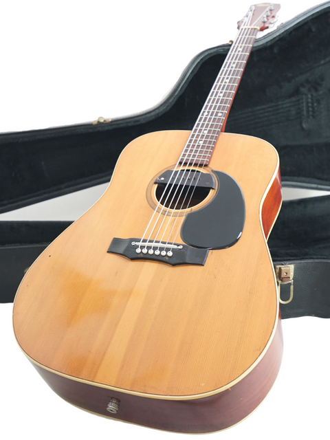 A 1972 Maton FG100 guitar in its case, featuring a stylish black strap, ready for a jam session.
