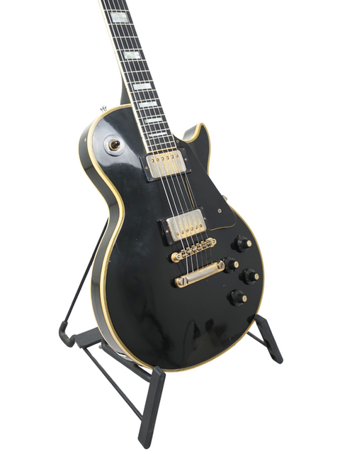 A 1973 Gibson Les Paul Custom Black Beauty electric guitar in black, showcased on a stand.