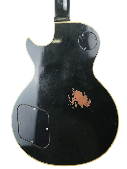 A 1973 Gibson Les Paul Custom Black Beauty guitar, showcasing a striking black finish with a distinctive white sticker.
