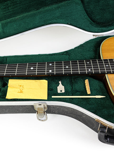 A 1976 Martin 000-28 guitar, elegantly placed in its case, with a guitar pick nearby, highlighting its vintage appeal.