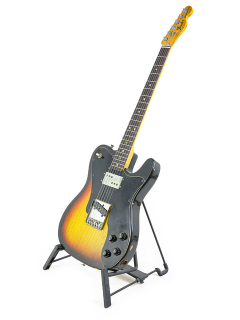 A 1977 Fender Telecaster Custom guitar on a stand, featuring a vibrant sunburst finish.