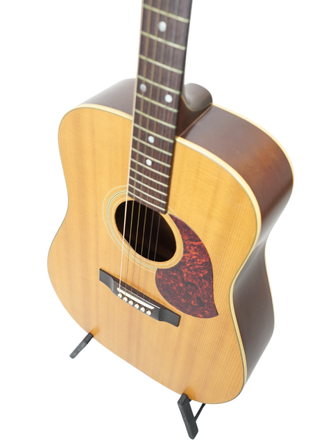 A 1991 Maton CW80/6 guitar displayed on a stand, set against a minimalist white backdrop.