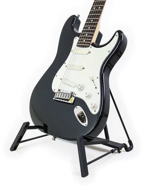 A 1991 USA Fender Strat Plus guitar in black, elegantly positioned on a stand with a white backdrop.