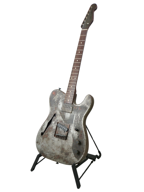 A 2006 James Trussart Steelcaster guitar displayed on a metal stand, featuring a striking design against a white backdrop.
