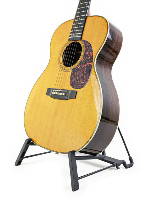 A 2006 Martin 000-28EC Eric Clapton Signature guitar displayed on a stand, set against a bright white backdrop.