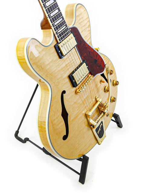 A 2011 Gibson Custom Shop ES-355 guitar displayed on a stand, set against a simple white backdrop.