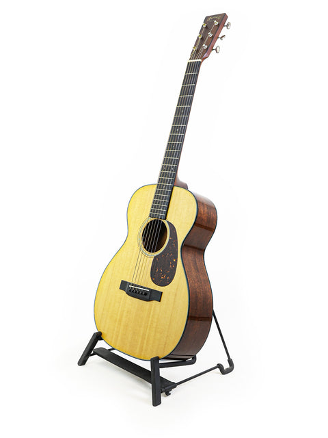 A 2021 Martin 0-18 acoustic guitar resting on a stand, highlighting its compact size and beautiful wood finish.