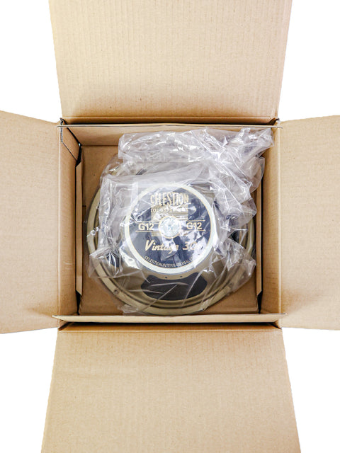 A Celestion speaker in plastic wrapping, packed inside a cardboard box.