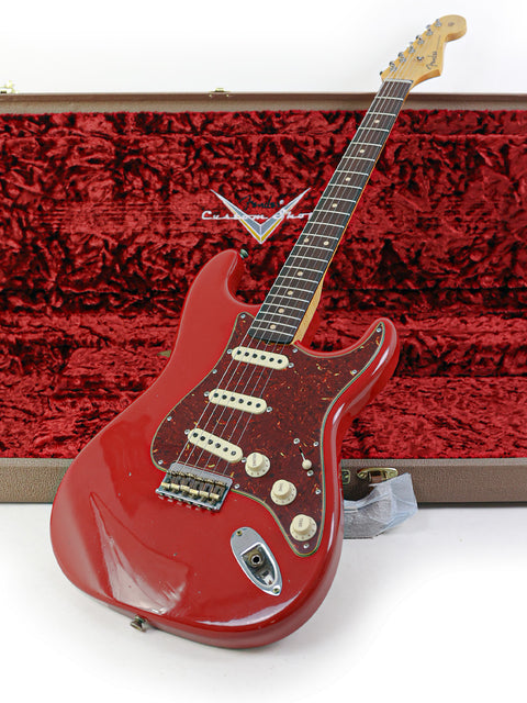 A Dakota Red Fender Custom Shop 1961 Stratocaster guitar in a case, featuring a beautifully crafted wooden body.