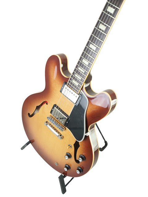 A Gibson Custom ES-335 guitar in Iced Tea color resting on a stand, highlighting its classic shape and premium quality.