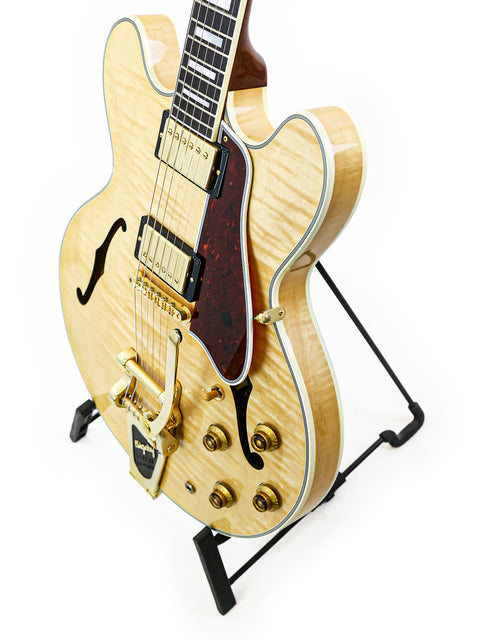 A Gibson Custom Shop ES-355 guitar from 2011 on a stand, presented with a minimalist white background for focus.