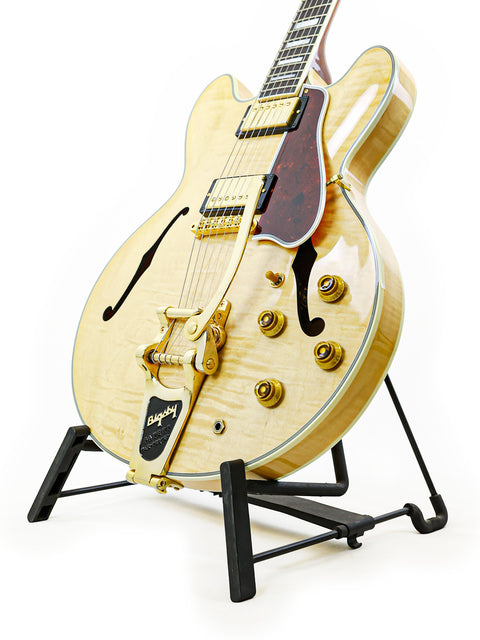 A Gibson Custom Shop ES-355 guitar from 2011 resting on a stand, set against a bright white background for emphasis.