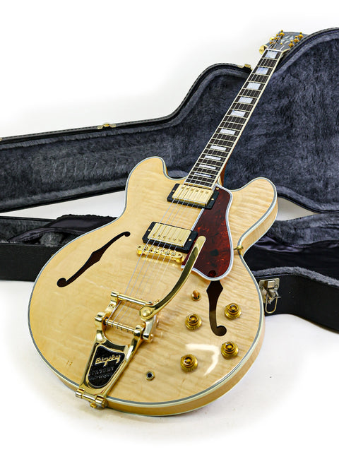 A Gibson Custom Shop ES-355 guitar with its case on the floor, highlighting the instrument's quality and vintage appeal.