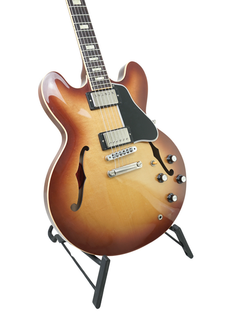 A Gibson ES-335 electric guitar in Iced Tea color on a stand, highlighting its classic shape and premium quality.