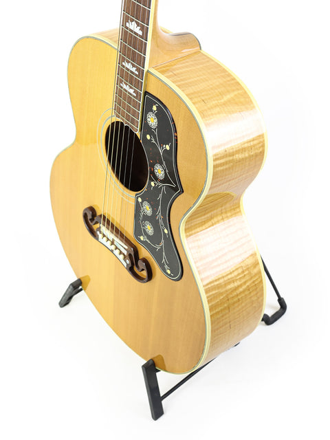 A Gibson SJ-200 guitar from 1999 displayed on a stand against a clean white background.