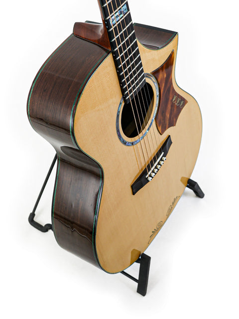 A James Cargill Custom guitar on a stand, set against a clean white background, showcasing its elegant design.
