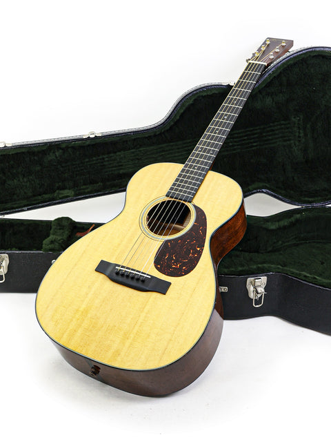 A Martin 0-18 guitar in a case, positioned on a white backdrop, emphasizing its beauty and quality from the USA, 2021.