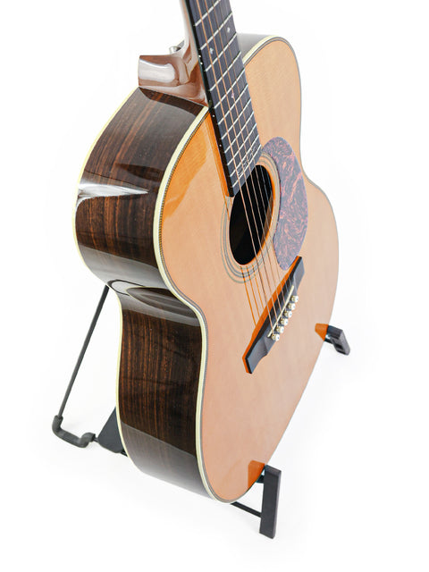 A Martin 000-28EC Eric Clapton Signature guitar on a stand against a clean white background, showcasing its elegant design.