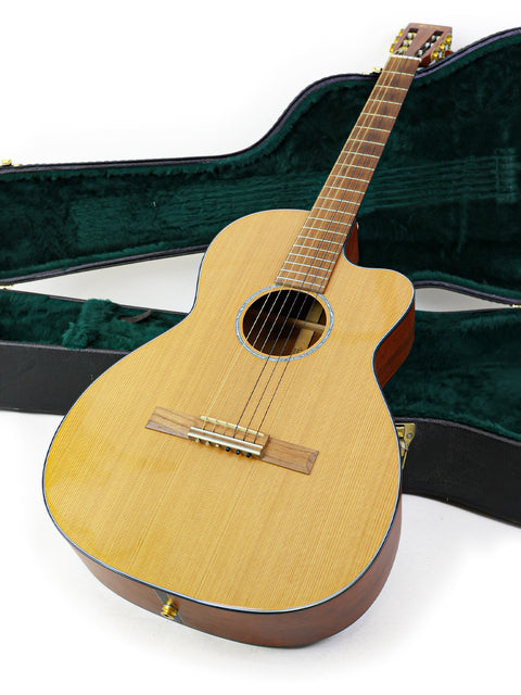 A Martin 000C-16SGCTNE guitar nestled in a green case, showcasing its elegant design and craftsmanship from 2003.