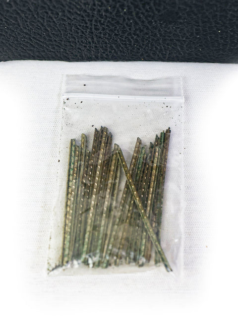 A bag of nails positioned on a black bag, featuring a vintage Martin 00-17 guitar from the USA, dated 1954.