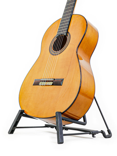 A beautifully crafted guitar on a stand, set against a stark white background, highlighting its features and Spanish origin, 1973.
