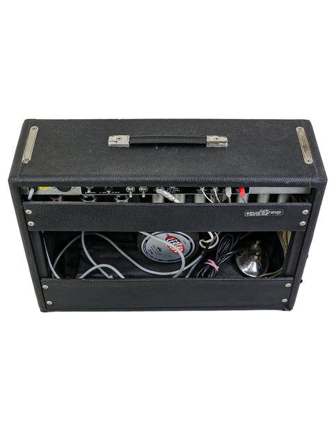 A black 1977 Fender Deluxe Reverb amp with a microphone and assorted electronic gear, perfect for live performances.