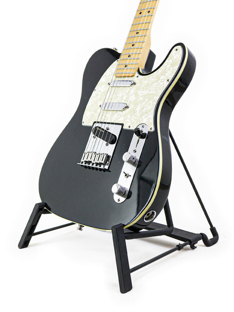 A black Fender Tele Plus V2 guitar from 1999 displayed on a stand against a clean white background.