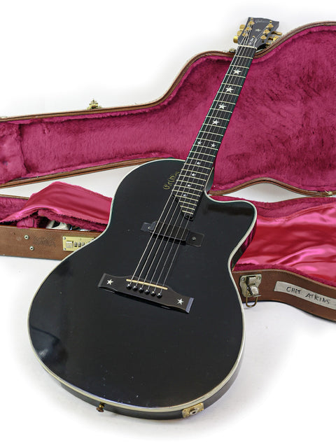 A black Gibson Chet Atkins SST guitar (2001) alongside its case, highlighting the instrument's craftsmanship and style.