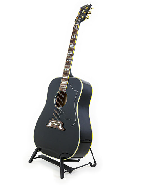 A black acoustic guitar, the Gibson Custom Shop Elvis Dove, displayed on a stand with a white backdrop.