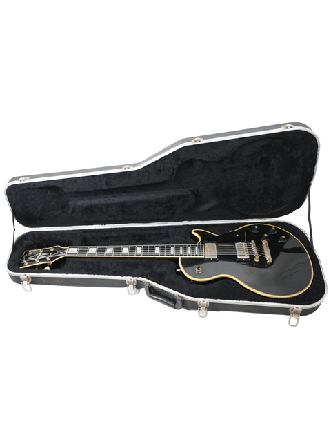 A black electric guitar, a 1973 Gibson Les Paul Custom Black Beauty, displayed within its protective case.