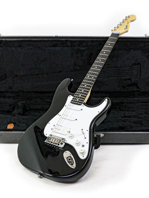 A black electric guitar, specifically a 1993 Fender Strat Plus Ultra, displayed within its protective case.