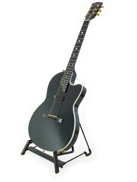 A black guitar, the Gibson Chet Atkins SST from 2001, elegantly positioned on a stand with a minimalist white backdrop.