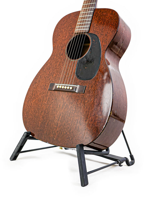 A classic 1954 Vintage Martin 00-17 guitar on a stand, contrasted against a white background, emphasizing its timeless beauty.